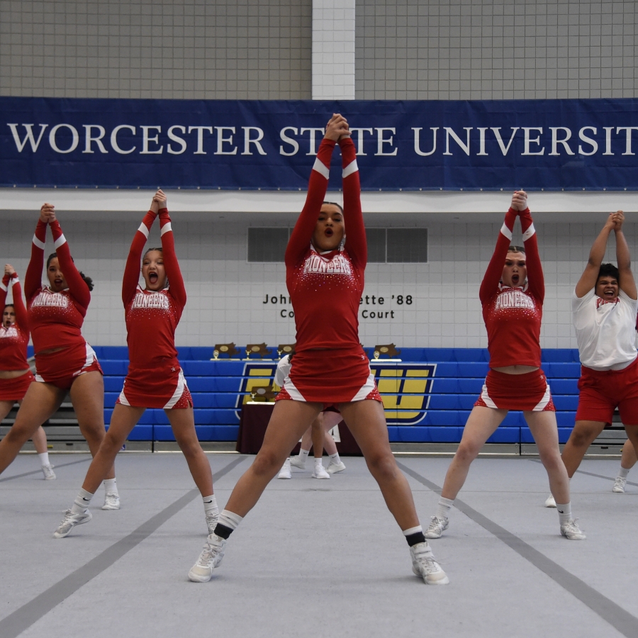 a cheer team poses for a photo in a gym